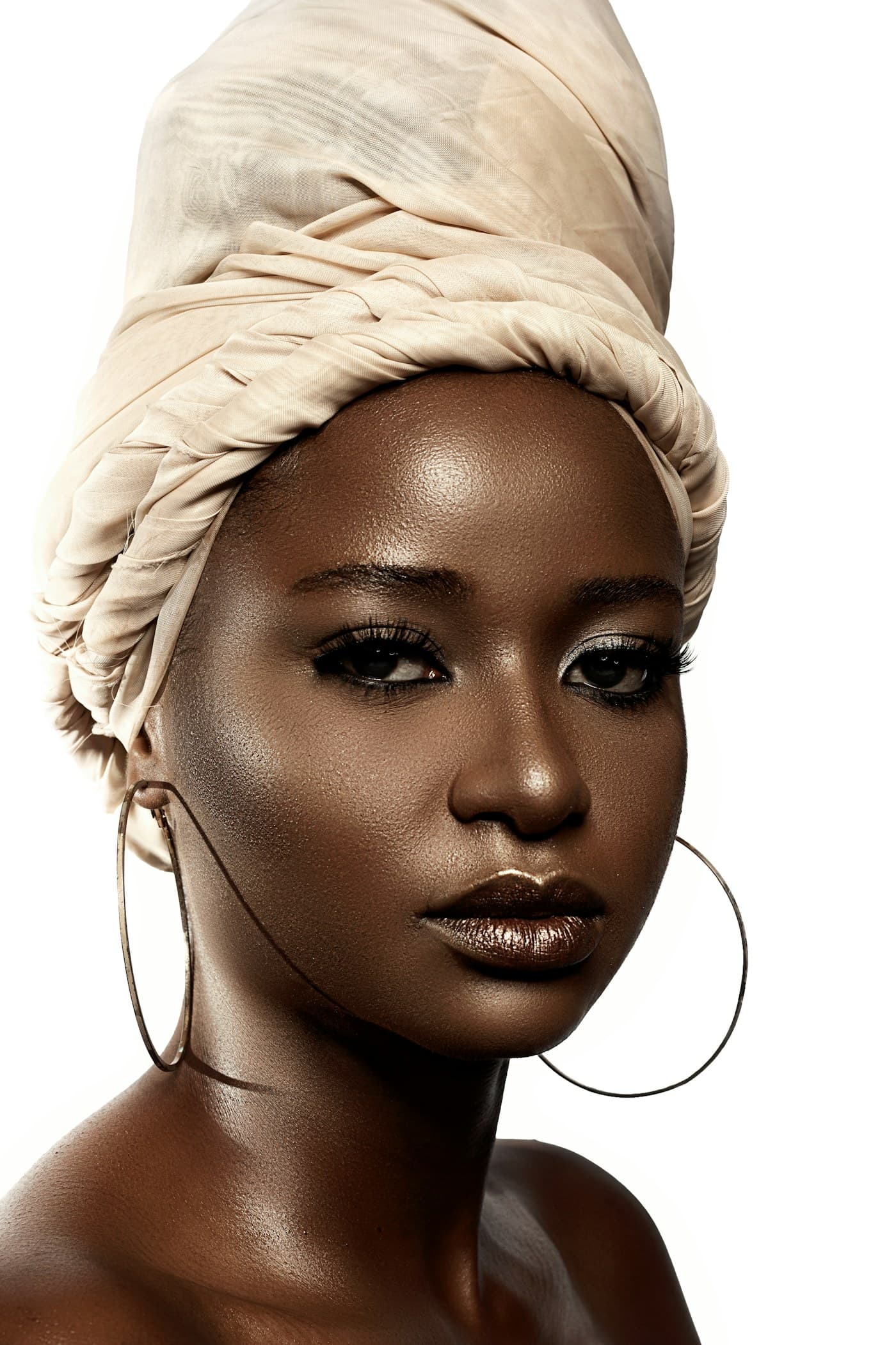 Woman in a cream head wrap with gold hoops