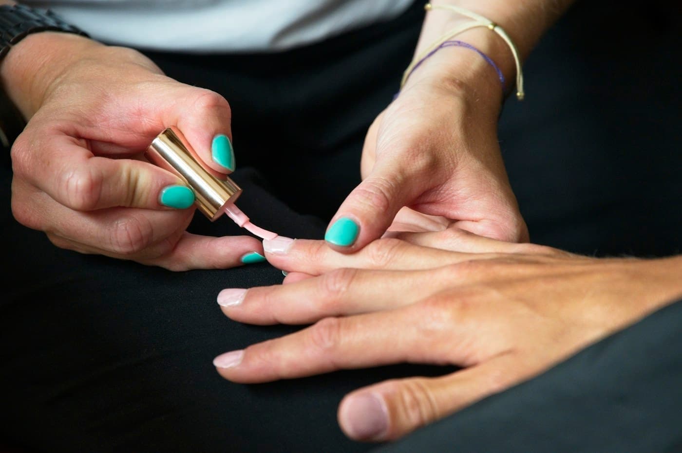Nail technician painting a client’s nails mint green
