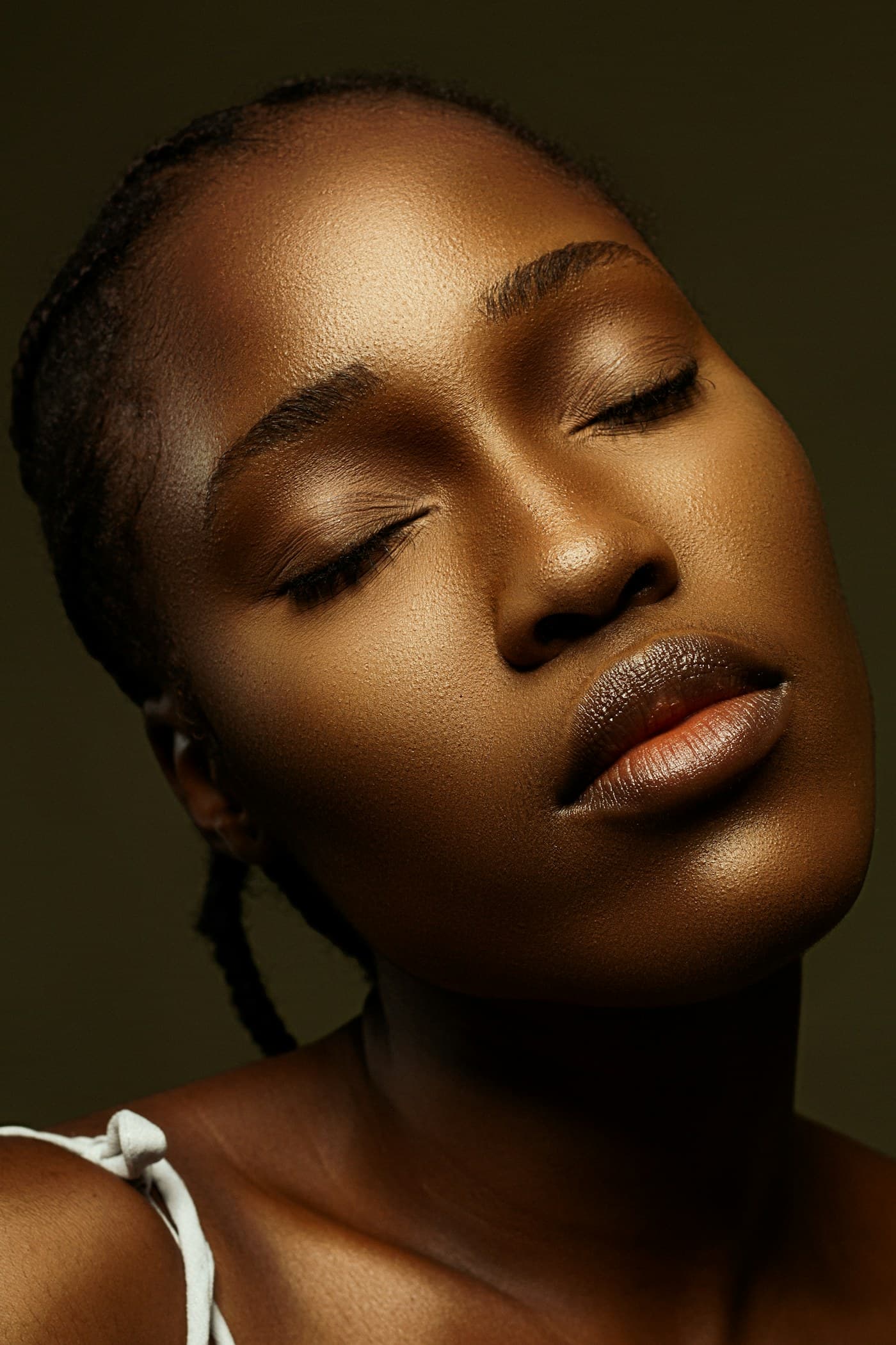 Woman with closed eyes and glowing bronze makeup